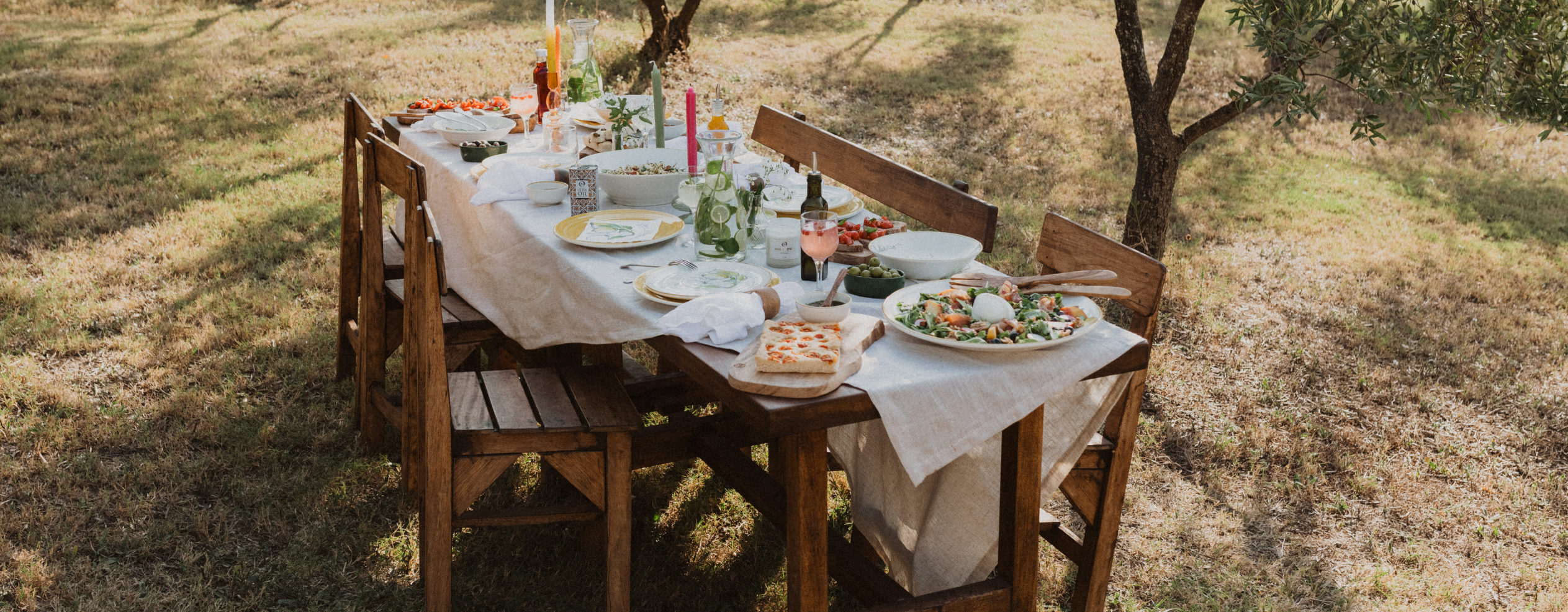 Tisch im freien. Gedeckt mit Salatschüsseln, Pizza, Olivenöl und schönen Servietten.